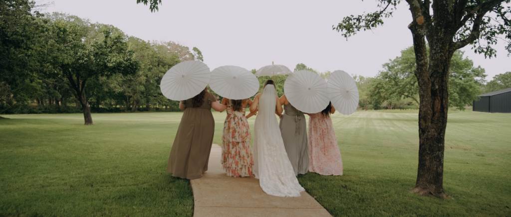 Dallas Wedding Videographer | Kaitlin and Isaiah | The Emerson Venue Wedding - bridesmaids walking with umbrellas