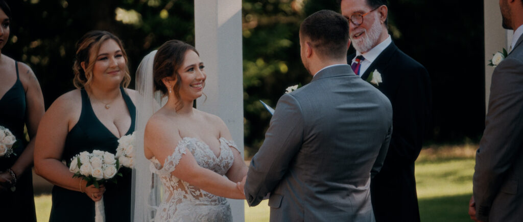 Dallas Wedding Videographer | Adrienne and John | Bethel Rock in Leonard, TX - bride smiling during outdoor ceremony