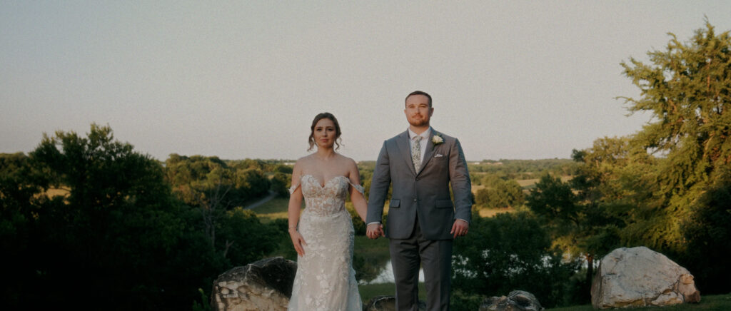 Dallas Wedding Videographer | Adrienne and John | Bethel Rock in Leonard, TX - couple standing holding hands looking at camera