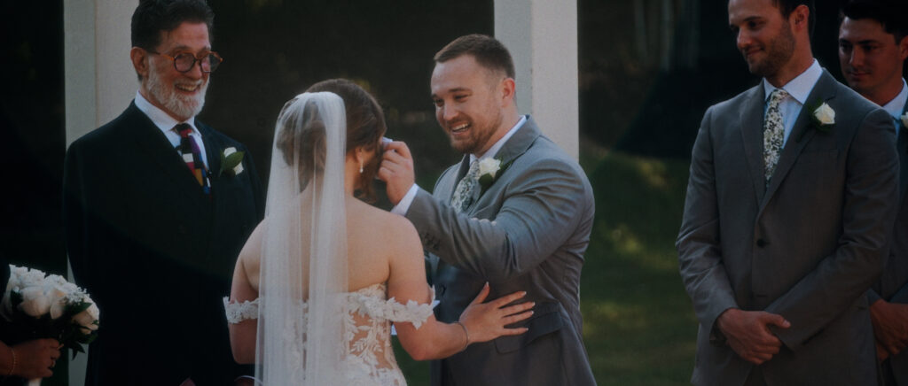 Dallas Wedding Videographer | Adrienne and John | Bethel Rock in Leonard, TX - groom wiping the bride's eyes during her vows