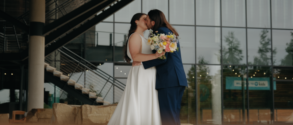 Dallas Wedding Videographer | Dana and Jordan | Watermark Church and HALL Arts Museum Wedding - Bride and Groom kissing outside of church